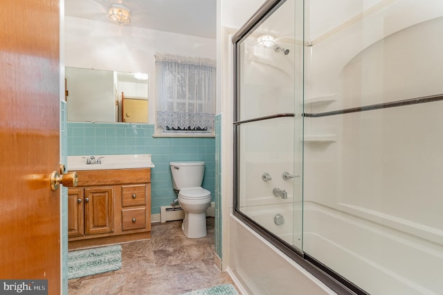 full bathroom featuring combined bath / shower with glass door, tile walls, a baseboard heating unit, vanity, and toilet