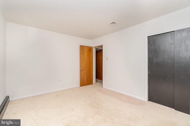 unfurnished bedroom featuring a closet, baseboard heating, and carpet