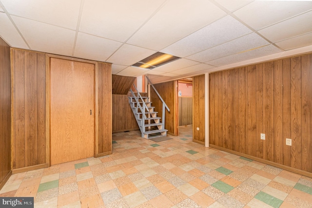 basement with wooden walls and a paneled ceiling