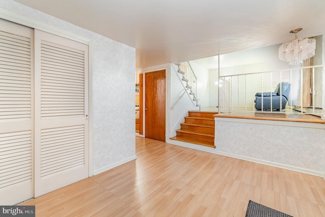 unfurnished living room with an inviting chandelier and light hardwood / wood-style floors