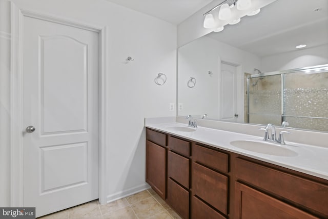 bathroom featuring tile patterned flooring, a sink, a shower stall, and double vanity