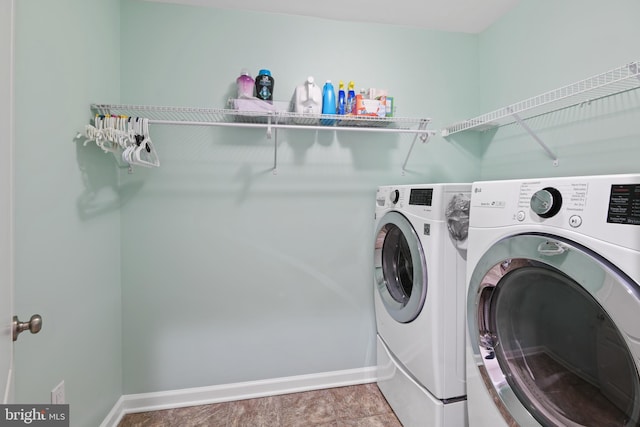 clothes washing area with laundry area, baseboards, and separate washer and dryer