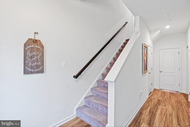 stairway with baseboards, wood finished floors, and recessed lighting