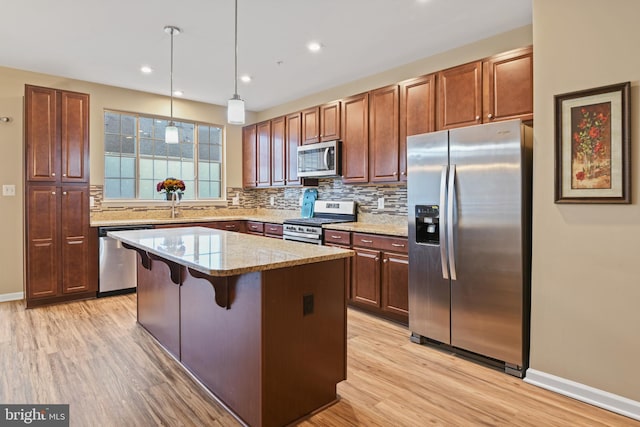 kitchen with light wood finished floors, appliances with stainless steel finishes, backsplash, and a center island