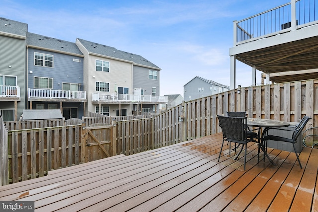 deck with a gate, fence, outdoor dining area, and a residential view