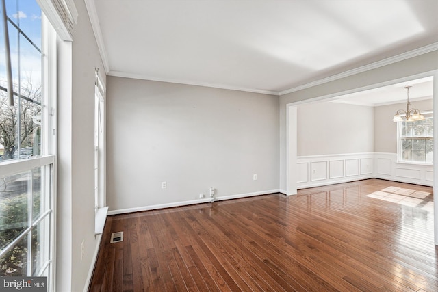 unfurnished room featuring hardwood / wood-style flooring, crown molding, and a chandelier