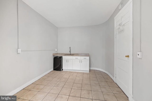 kitchen with white cabinetry, sink, light tile patterned floors, and dishwasher