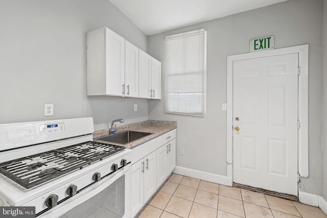 kitchen featuring sink, light tile patterned floors, gas range gas stove, and white cabinets