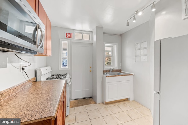 kitchen featuring sink, light tile patterned floors, track lighting, and white appliances