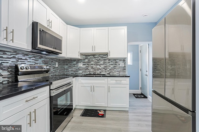 kitchen featuring stainless steel appliances, white cabinetry, sink, and decorative backsplash