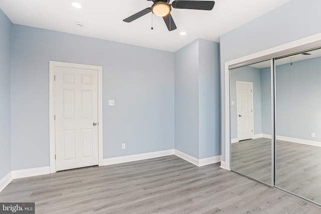 unfurnished bedroom featuring ceiling fan, light hardwood / wood-style floors, and a closet