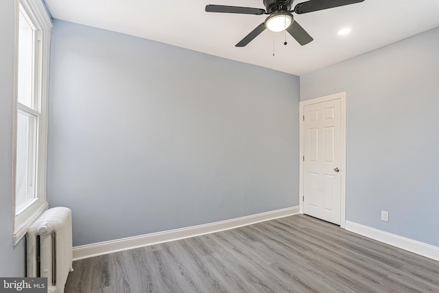 empty room with hardwood / wood-style flooring, ceiling fan, and radiator