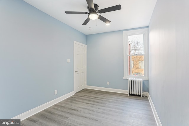 spare room featuring radiator, light hardwood / wood-style floors, and ceiling fan