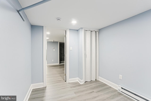 empty room featuring baseboard heating and light hardwood / wood-style flooring