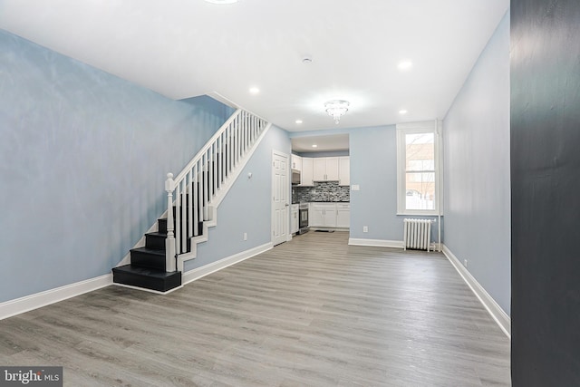 unfurnished living room with radiator heating unit and light wood-type flooring