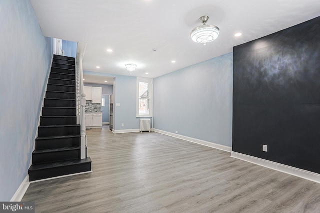 unfurnished living room featuring radiator heating unit and light wood-type flooring