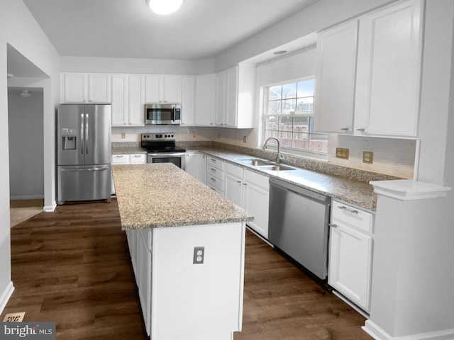 kitchen with sink, a center island, appliances with stainless steel finishes, dark hardwood / wood-style flooring, and white cabinets