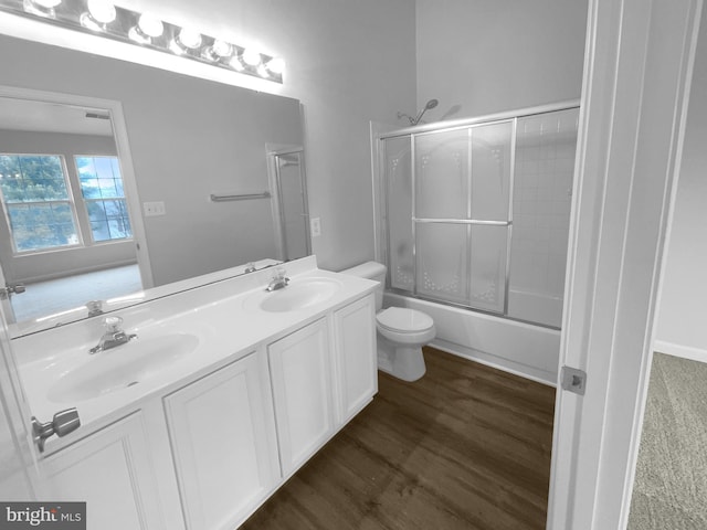 full bathroom featuring vanity, hardwood / wood-style floors, shower / bath combination with glass door, and toilet