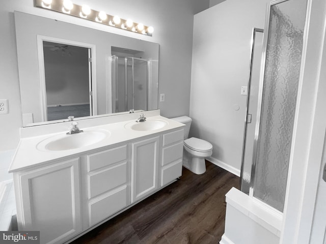 bathroom with wood-type flooring, toilet, a shower with shower door, and vanity