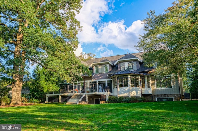 back of house featuring a sunroom, a deck, and a lawn