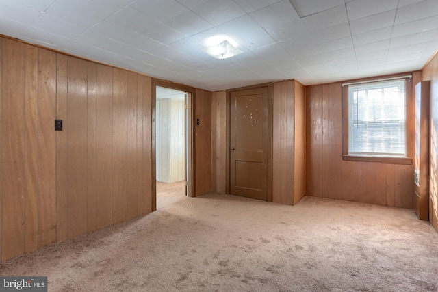 carpeted empty room featuring wood walls