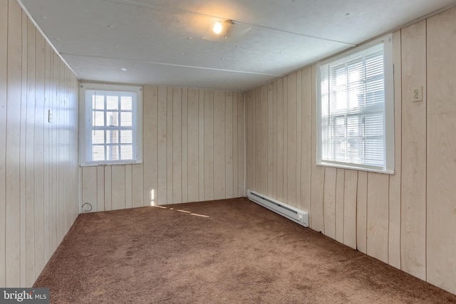 carpeted spare room featuring wooden walls and a baseboard heating unit