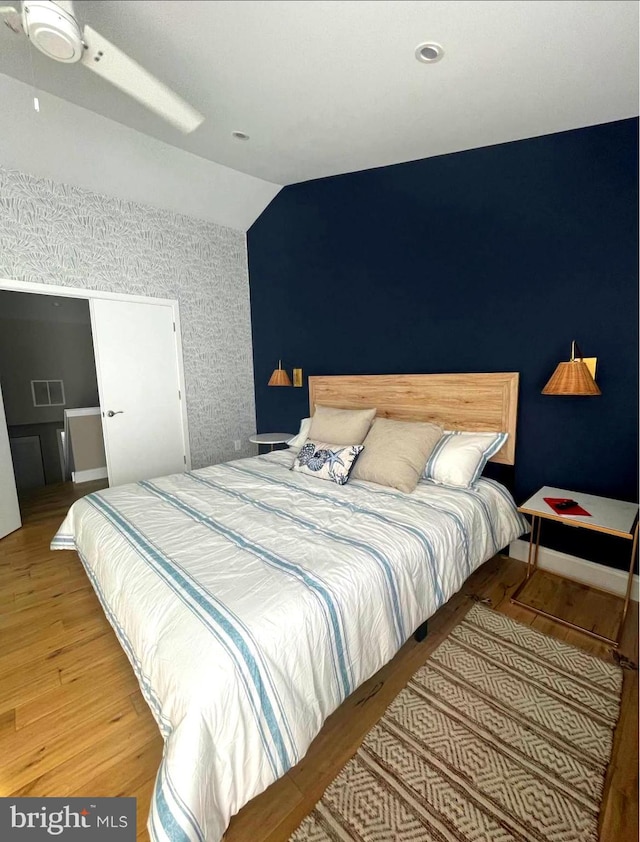 bedroom with vaulted ceiling, wood finished floors, visible vents, and baseboards