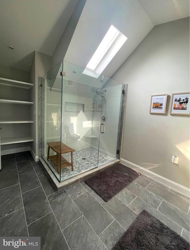 full bath with lofted ceiling with skylight, a shower stall, and baseboards