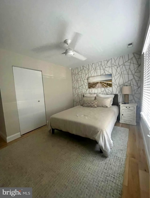 bedroom with visible vents, wood finished floors, and a ceiling fan