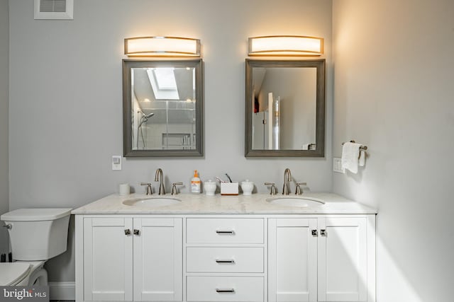 full bath with visible vents, a sink, toilet, and double vanity