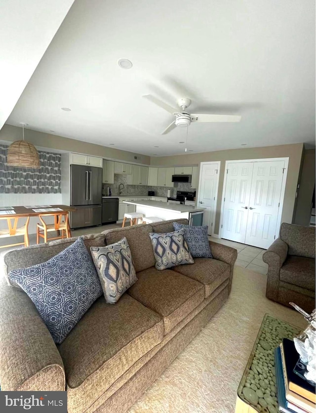 living area with a ceiling fan and tile patterned floors