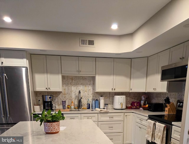 kitchen featuring white cabinetry, visible vents, stainless steel appliances, and a sink