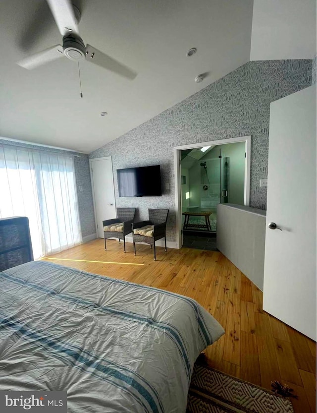 bedroom featuring a ceiling fan, lofted ceiling, wallpapered walls, and wood finished floors