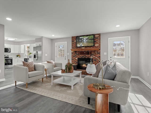 living room featuring recessed lighting, a healthy amount of sunlight, a fireplace, and wood finished floors