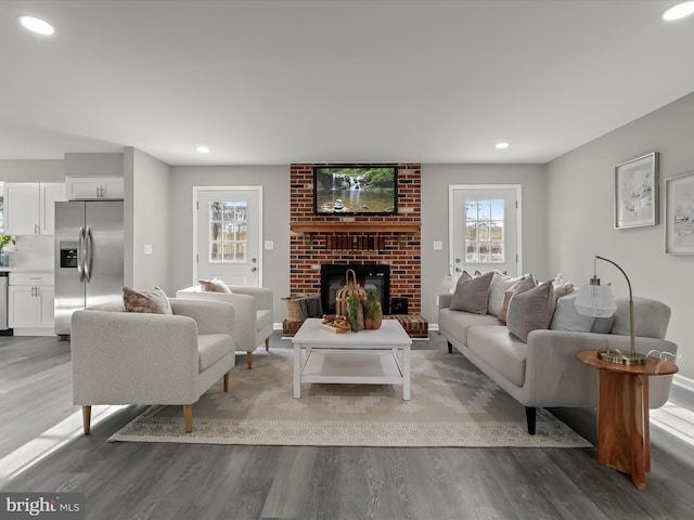 living area featuring recessed lighting, a brick fireplace, and wood finished floors