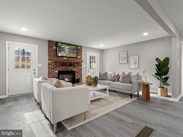 living area featuring recessed lighting, a fireplace, wood finished floors, and baseboards