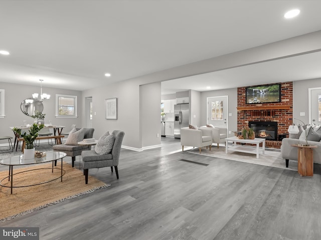 living room featuring an inviting chandelier, a fireplace, wood finished floors, and recessed lighting