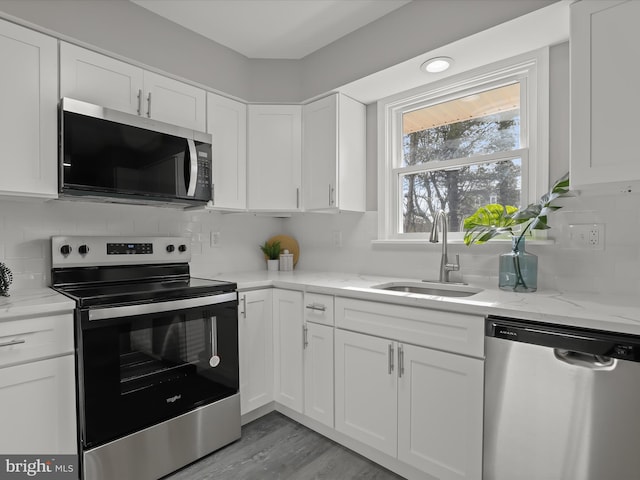 kitchen featuring appliances with stainless steel finishes, white cabinetry, a sink, and backsplash