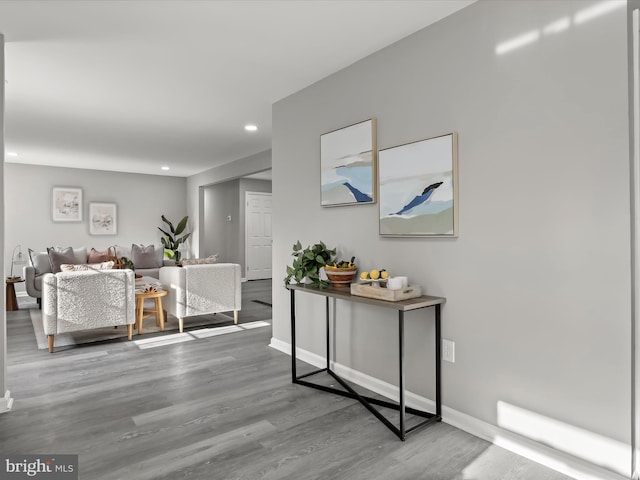 hall featuring baseboards, wood finished floors, and recessed lighting