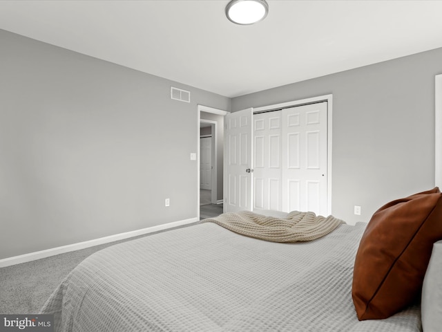 carpeted bedroom with a closet, visible vents, and baseboards