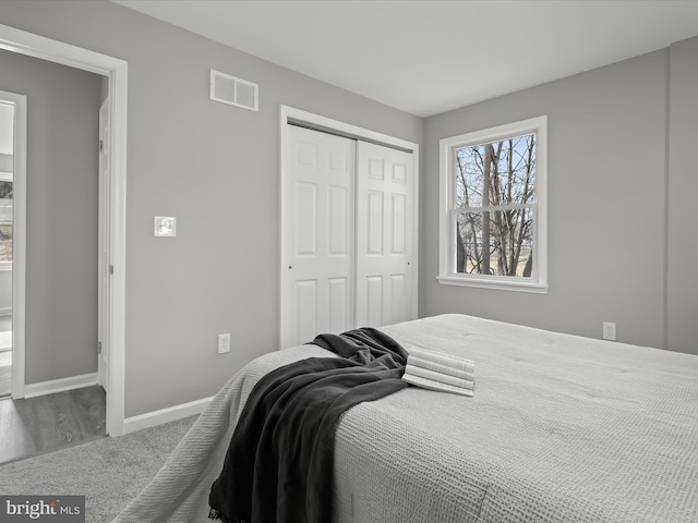 bedroom with dark colored carpet, a closet, visible vents, and baseboards