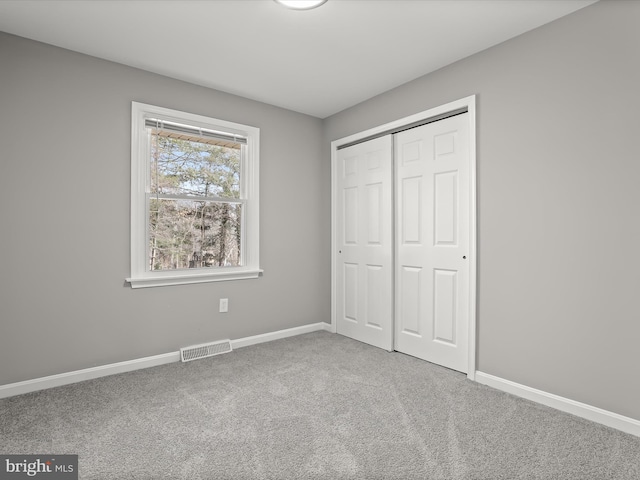 unfurnished bedroom featuring baseboards, a closet, visible vents, and carpet flooring