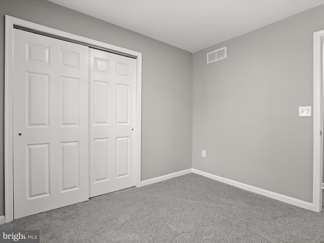 unfurnished bedroom with a closet, carpet, visible vents, and baseboards