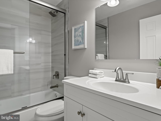 bathroom with enclosed tub / shower combo, vanity, and toilet