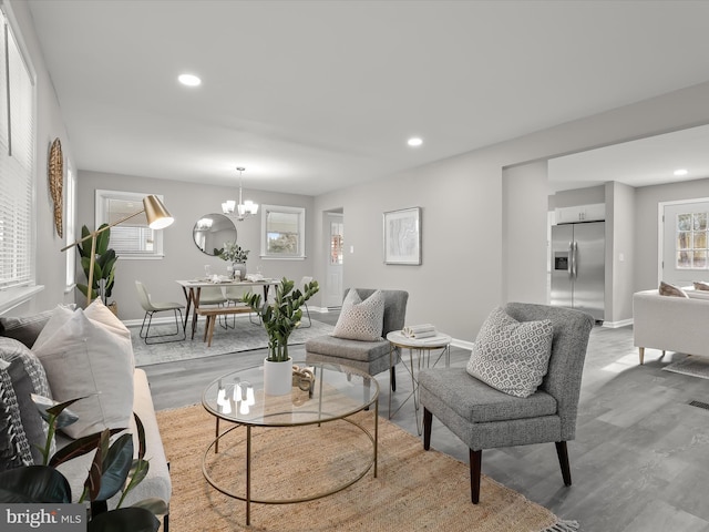 living area with light wood-style floors, recessed lighting, a notable chandelier, and baseboards