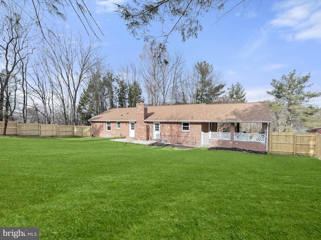 rear view of house with a fenced backyard, brick siding, a yard, crawl space, and a chimney