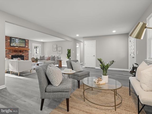 living room featuring baseboards, a brick fireplace, wood finished floors, and recessed lighting