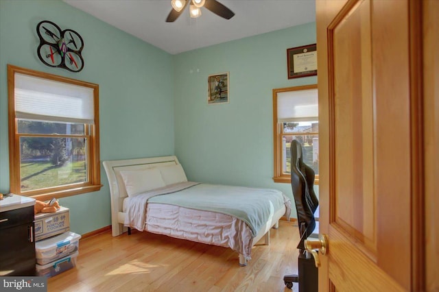 bedroom featuring ceiling fan, light hardwood / wood-style floors, and multiple windows