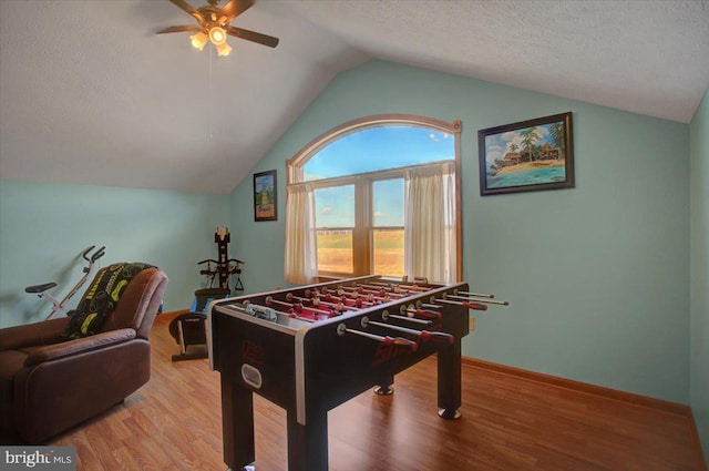 game room with ceiling fan, lofted ceiling, a textured ceiling, and light wood-type flooring