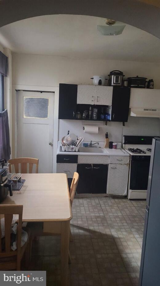 kitchen featuring gas range, sink, and white fridge